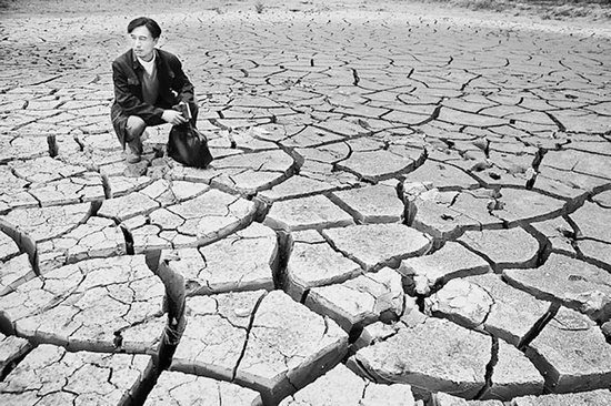 蹲在干涸的田地里，焦裕祿為饑餓的百姓揪心不已 《焦裕祿》劇照